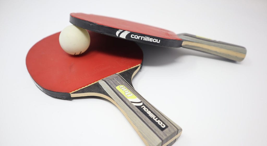 a pair of ping pong paddles and a ball